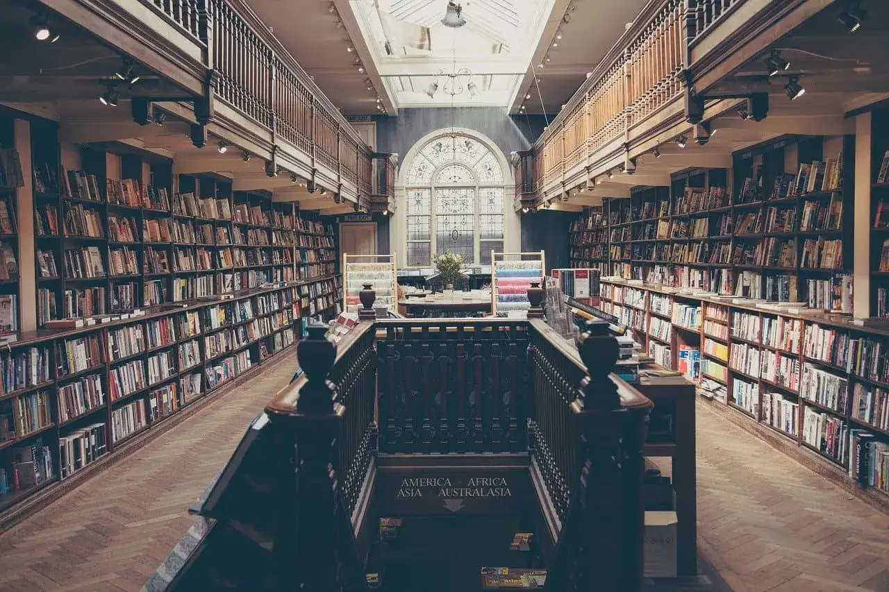 Wielka biblioteka z regałami pełnymi książek, idealna do studiów prawniczych. Wnętrze z drewnianymi balustradami i łukowym oknem.
