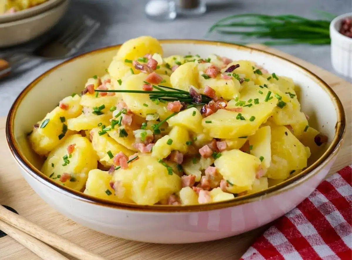 Sch&uuml;ssel mit warmem Kartoffelsalat, garniert mit Speckw&uuml;rfeln und Schnittlauch. Ein Klassiker, der immer schmeckt!