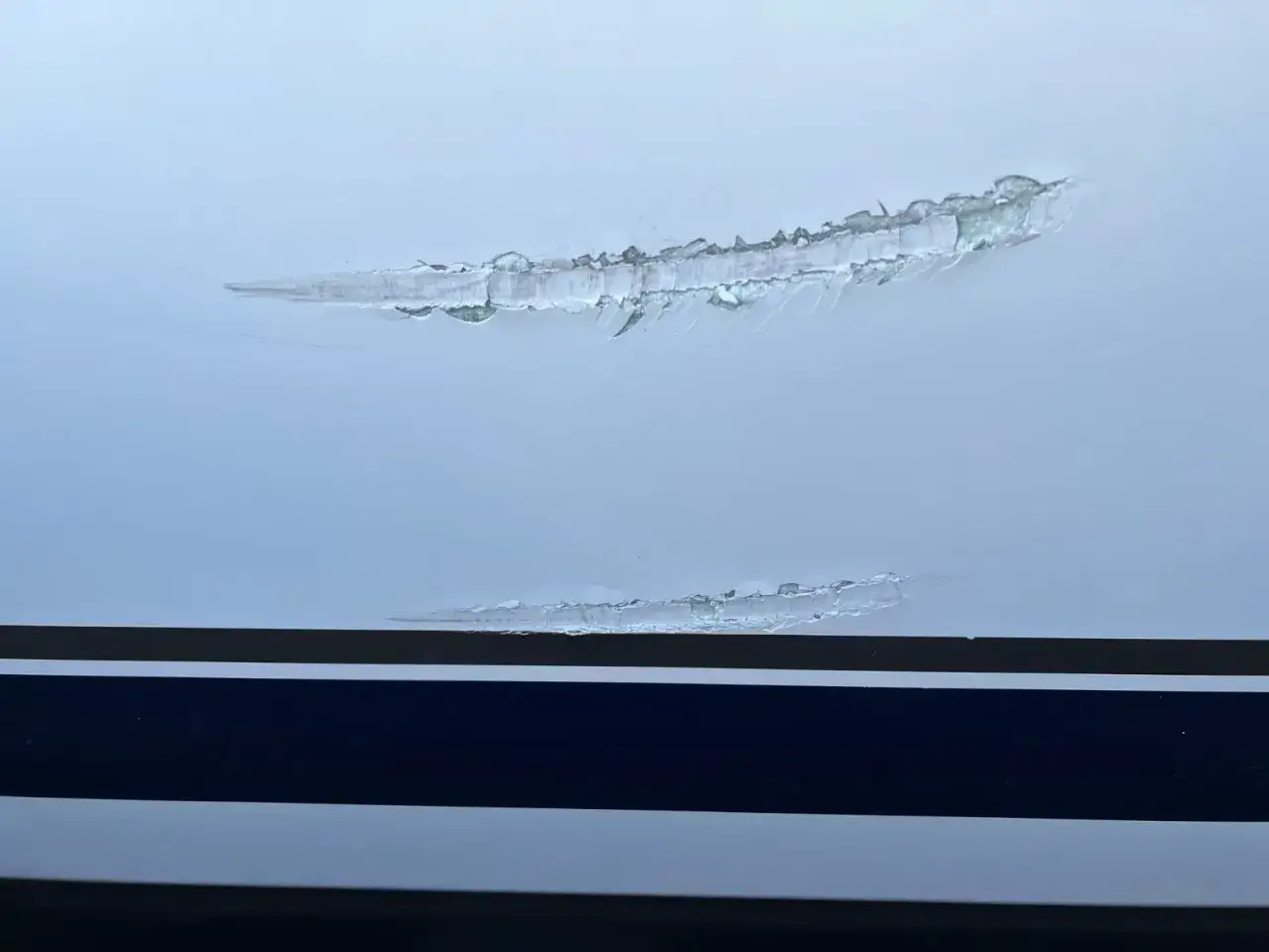 Beschädigter Gelcoat, der erneuert werden muss. Kratzer auf der Oberfläche zeigen, dass eine Reparatur nötig ist.