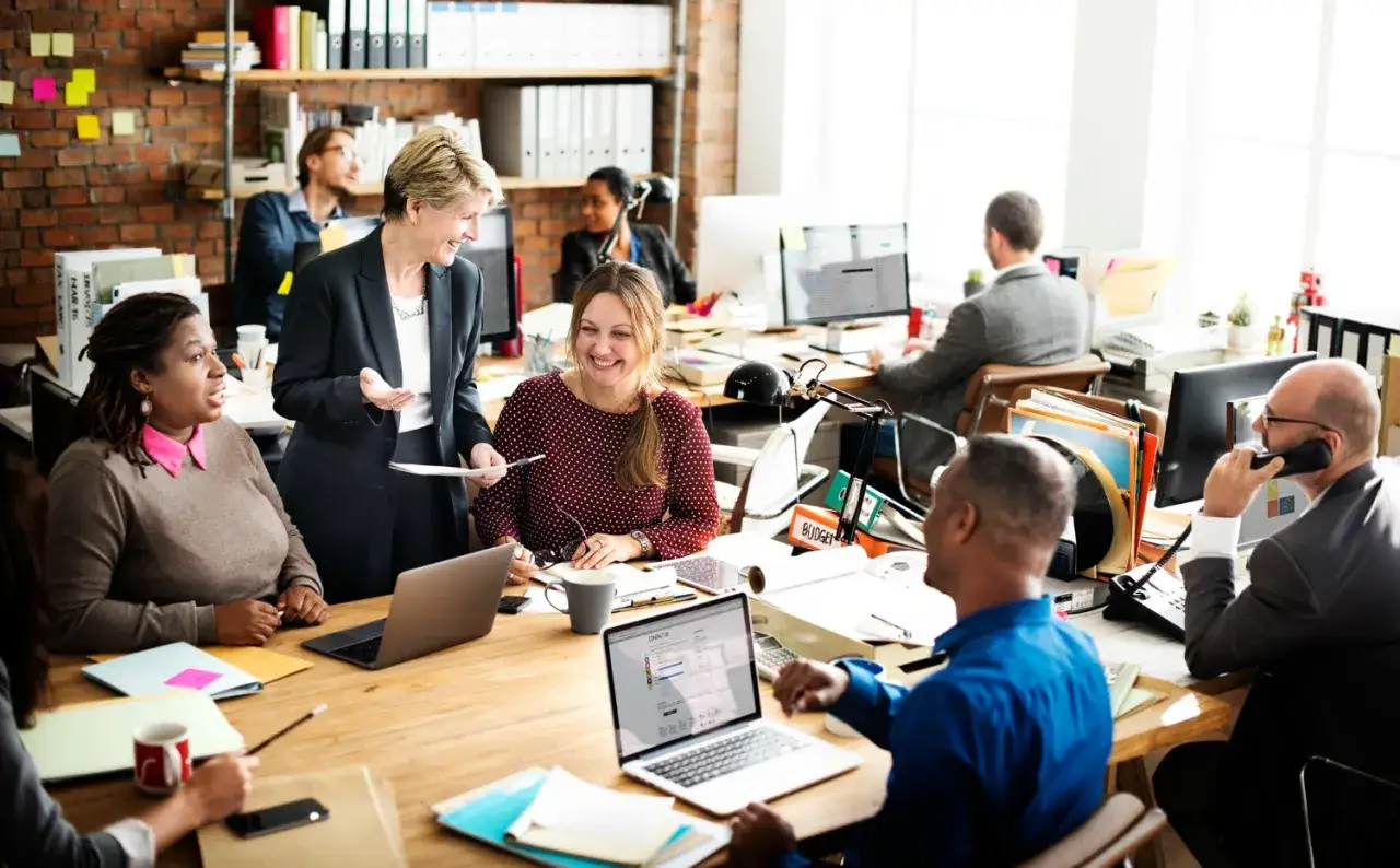 A diverse team collaborates in a bright office, fostering a positive atmosphere and increasing employee morale.