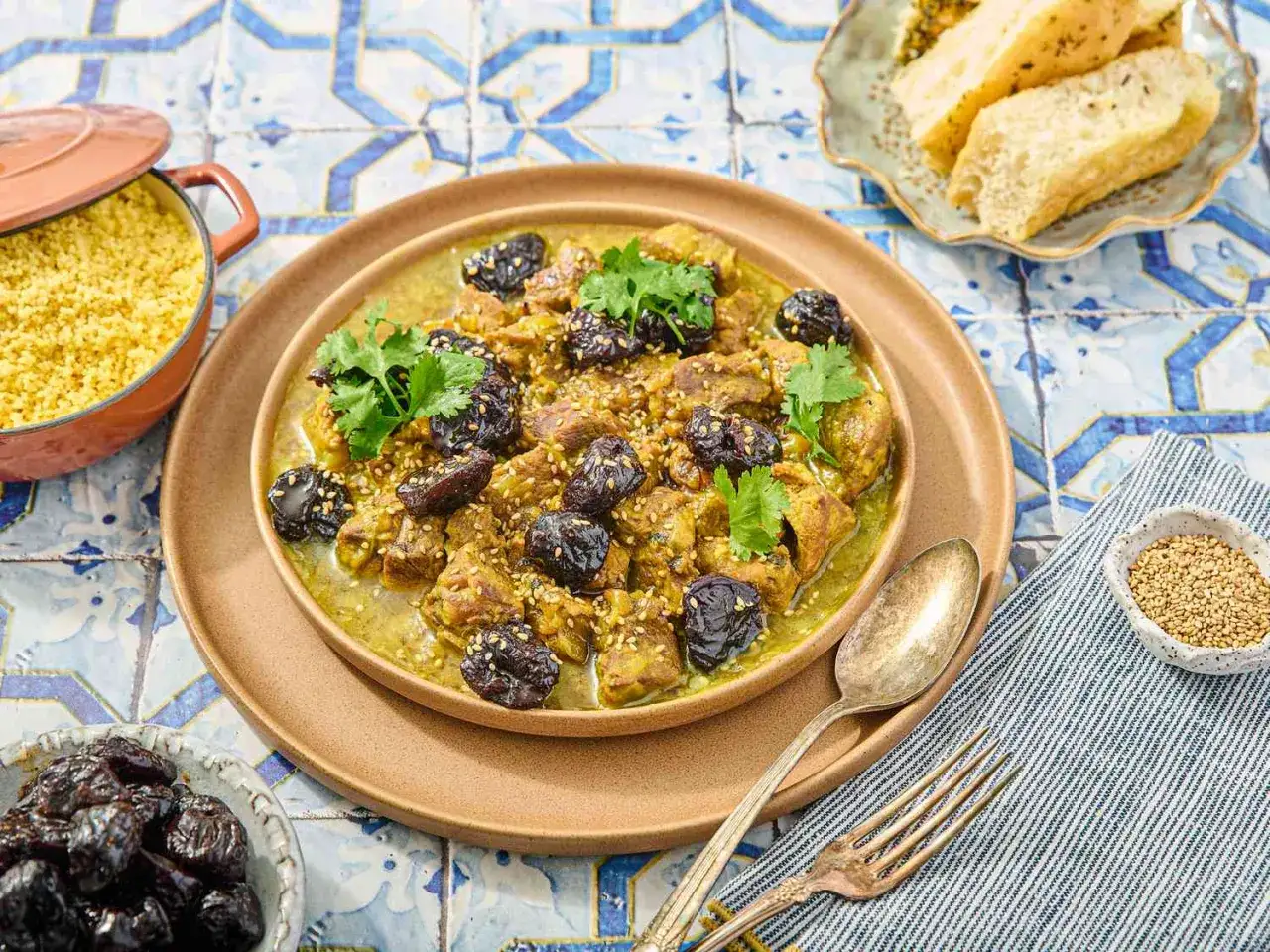 Tajín de cordero con ciruelas pasas y cilantro, servido con cuscús y pan.