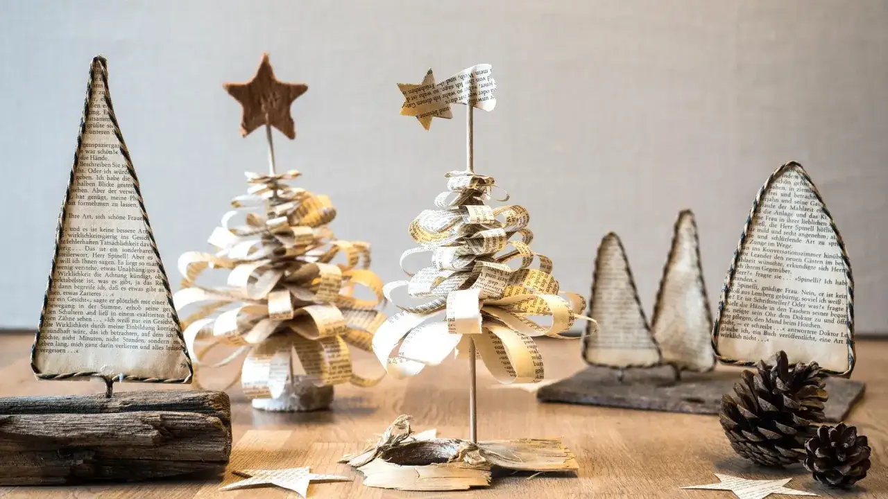 Deko basteln mit alten Buchseiten: Kleine, handgefertigte Weihnachtsb&auml;ume aus Papier, verziert mit Sternen.