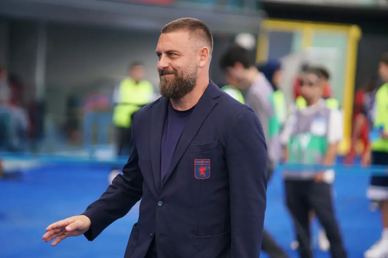 Włochy mistrzostwa świata: mężczyzna z brodą w granatowej marynarce z herbem, w tle rozmyte postacie.