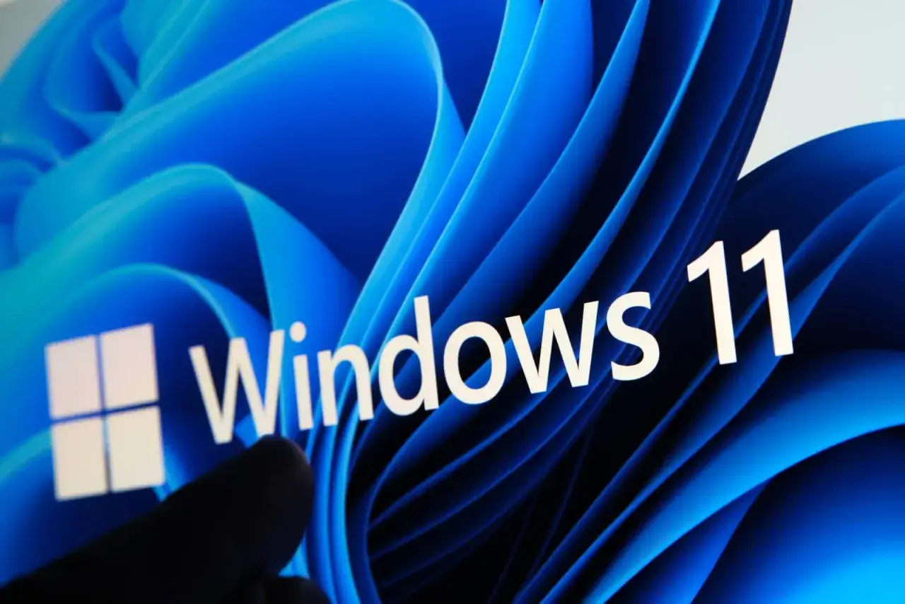 Palec dotyka ekranu z logo Windows 11. Czy Twój komputer działa wolno? Czas na optymalizację Windows 11!