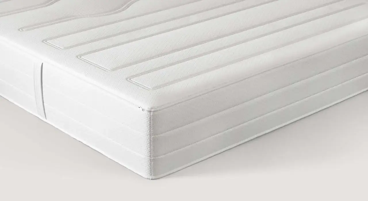 Un matelas blanc aux lignes matelassées, dont la matière latex offre un confort optimal pour un sommeil réparateur.