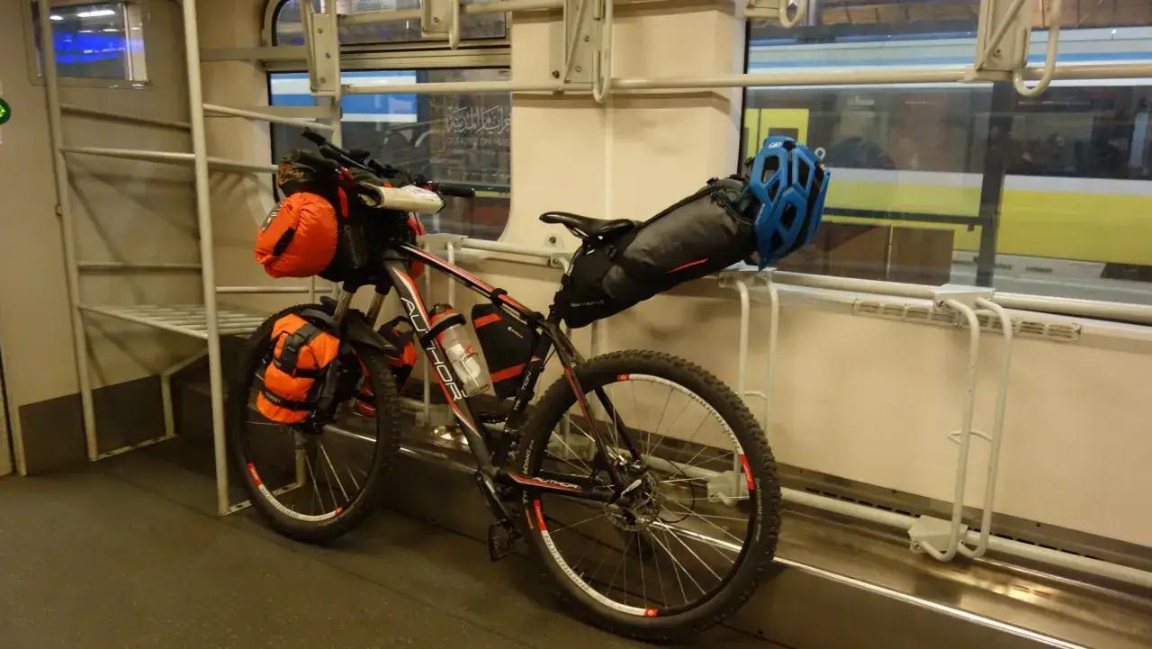 Rower z sakwami i kaskiem czeka na podróż. Oto jak powiesić rower w pociągu, wykorzystując dostępne uchwyty.