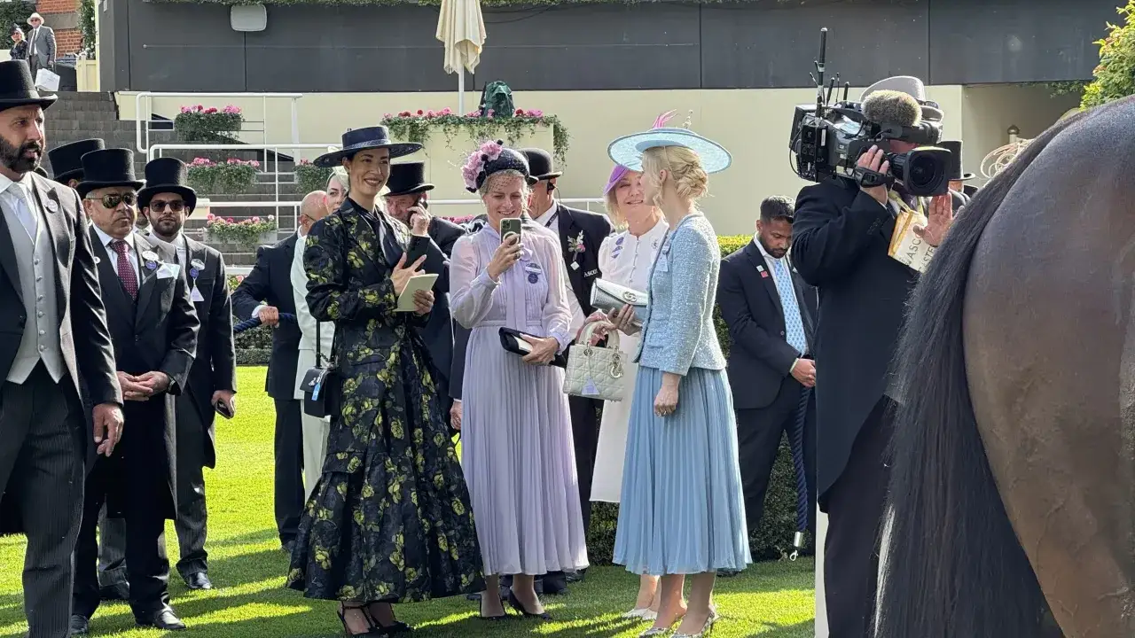 Elegante Damen und Herren in festlicher Kleidung, die dem Ascot Pferderennen Dresscode folgen, posieren f&uuml;r die Kameras.