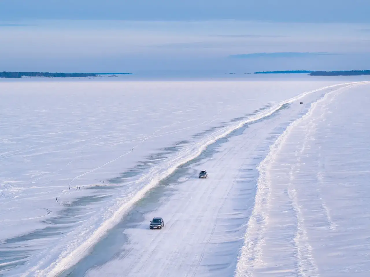 Vinterlandskap vid Lule&aring; med bilar p&aring; en isv&auml;g. Sn&ouml; och is t&auml;cker landskapet.
