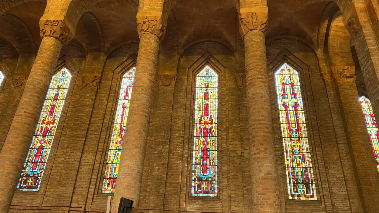 Vitraux color&eacute;s illuminant l'int&eacute;rieur de l'&eacute;glise de Gien, entre piliers de briques et vo&ucirc;tes.