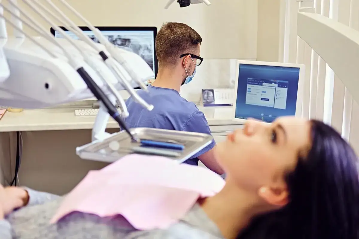 Pacjentka u dentysty, który analizuje wyniki badań. Warto wiedzieć, na ile dentysta może wystawić L4.