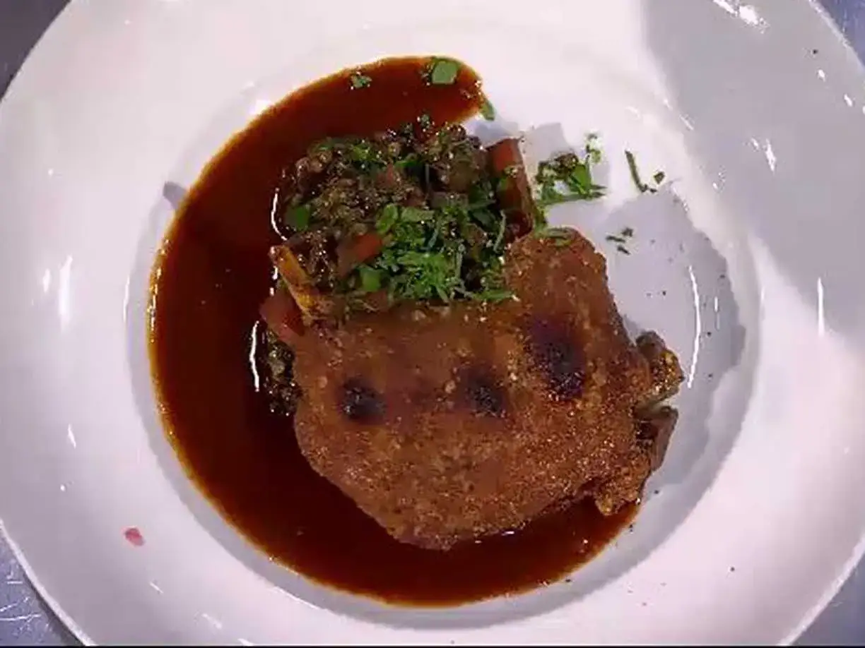 En krispig confiterad anka serveras med en mustig sås och en grönsaksblandning toppad med färska örter.