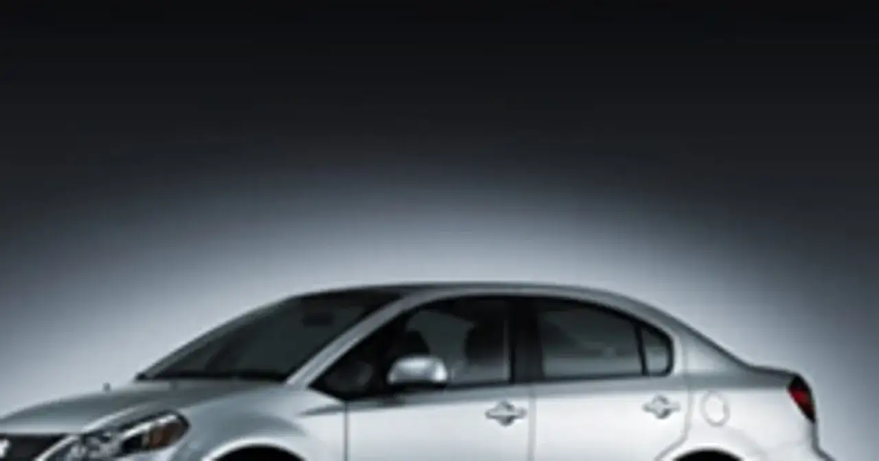 Srebrny sedan Suzuki SX4 prezentuje się elegancko na ciemnym tle.