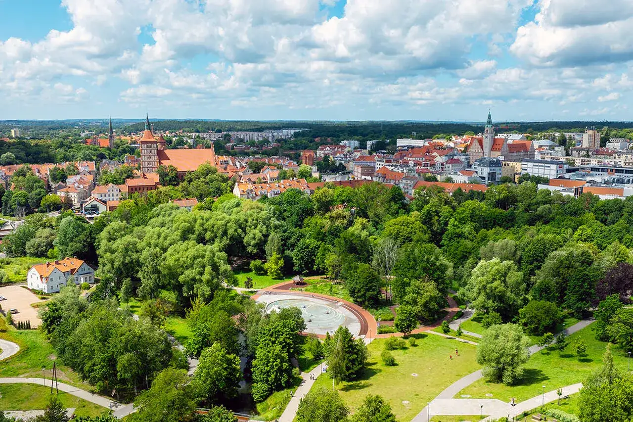 Olsztyn: malowniczy widok na miasto z zielonym parkiem i fontanną. Idealne miejsce, by zobaczyć, co zwiedzić w Olsztynie.