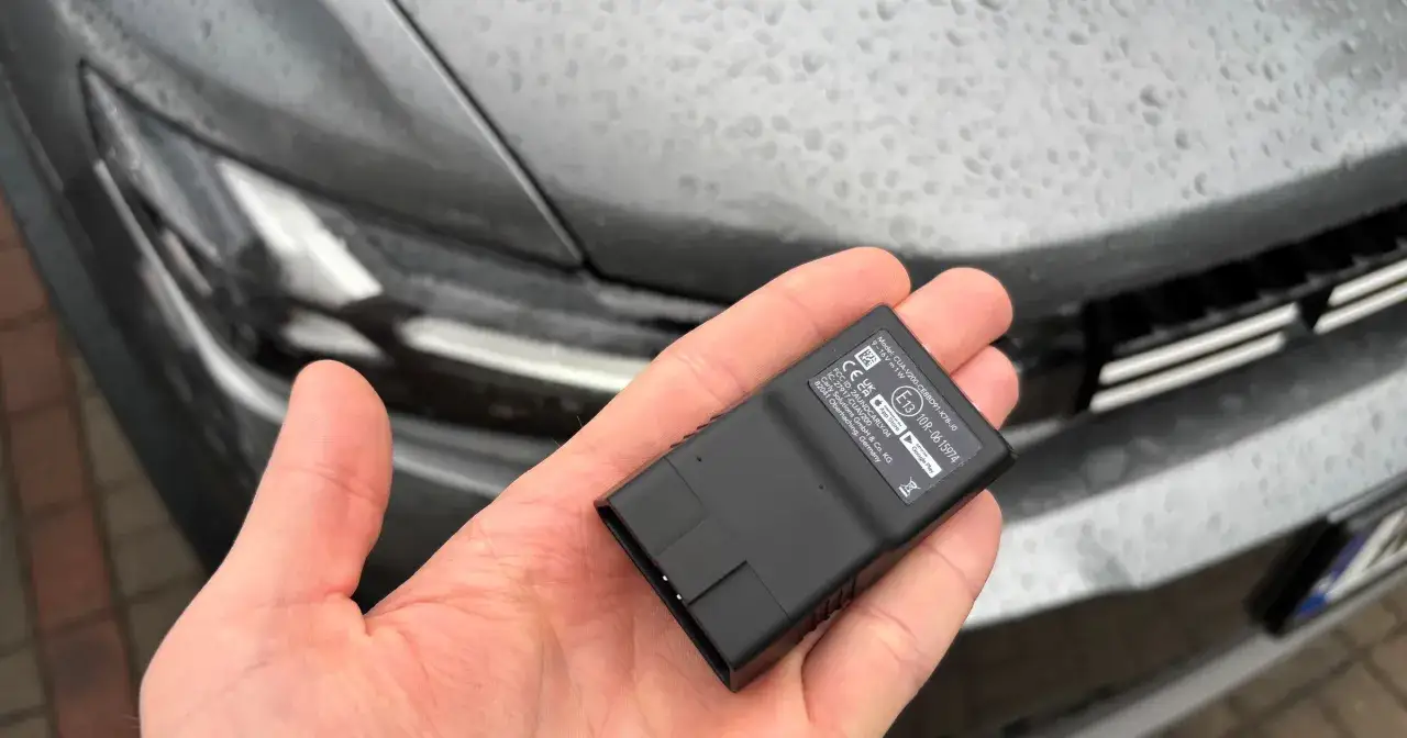 Mały czarny adapter OBD w dłoni, gotowy do podłączenia do samochodu. To właśnie obd, co to jest? Narzędzie diagnostyczne.