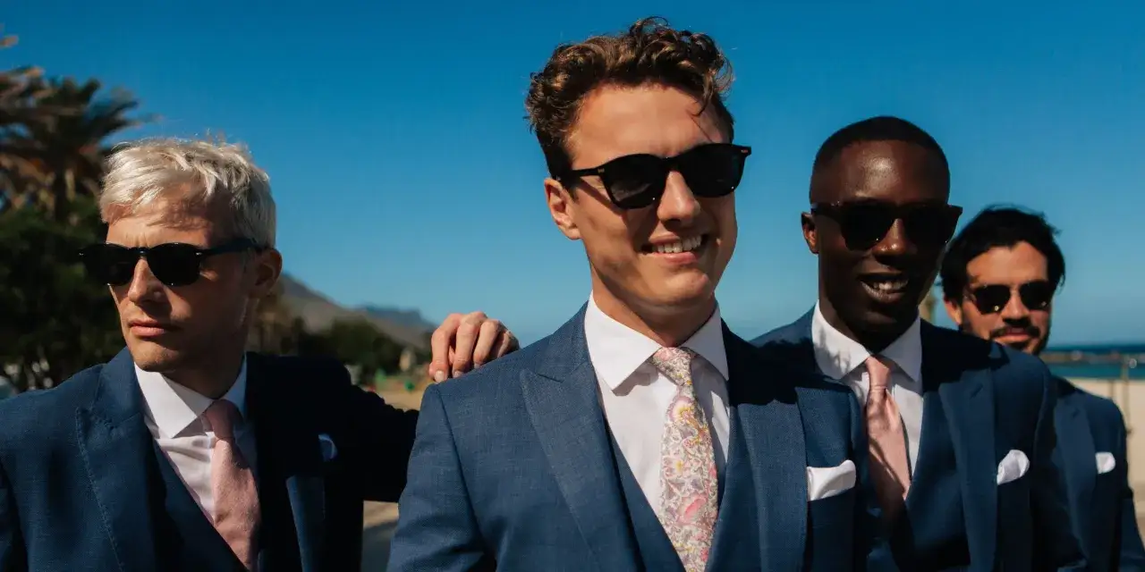 Four men in blue suits and sunglasses, ready for a 