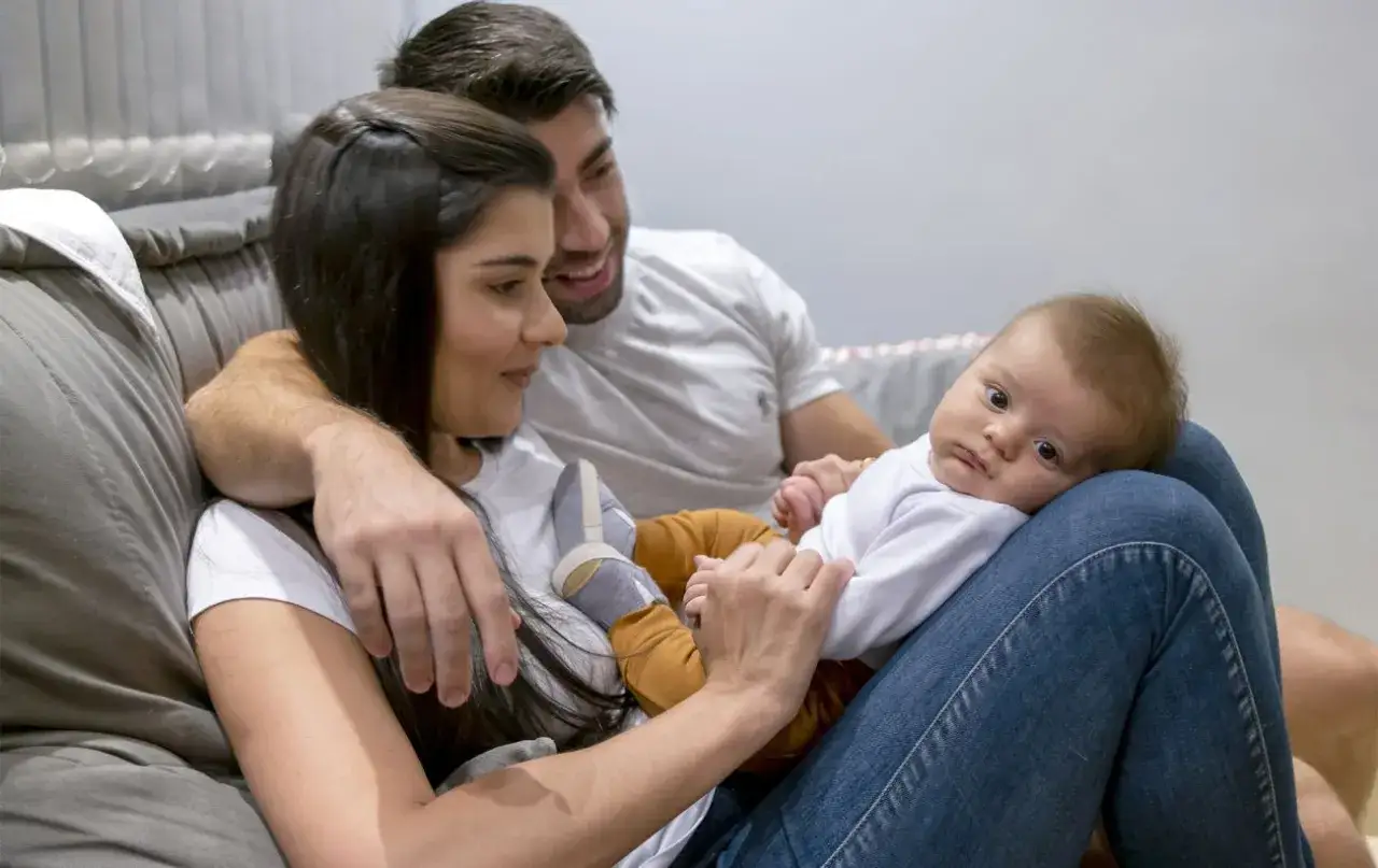 Rodzice z czułością patrzą na swoje dziecko. Mimo zmęczenia, ich oczy błyszczą miłością, a nie **baby blues**.