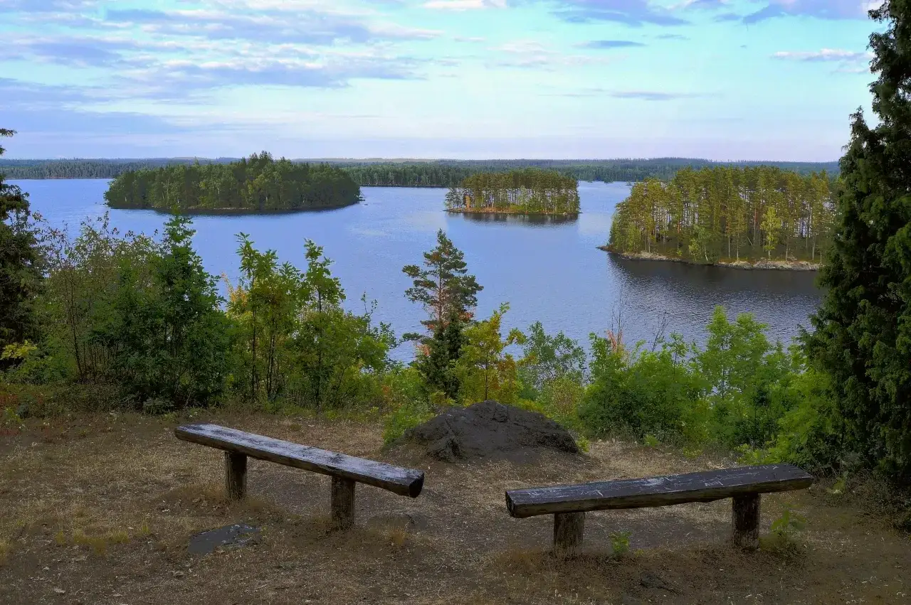 Tv&aring; b&auml;nkar bjuder in till en paus under en vandring i Sm&aring;land, med utsikt &ouml;ver en stilla sj&ouml; och gr&ouml;nskande &ouml;ar.