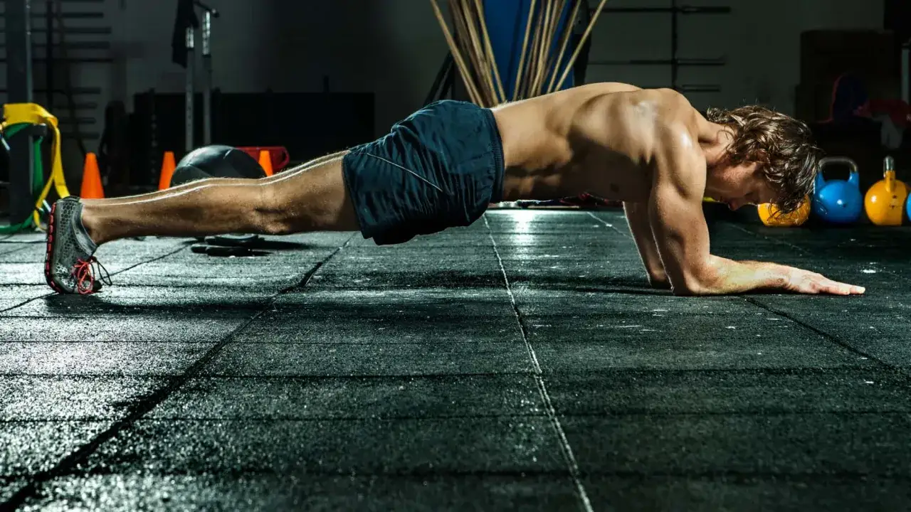 Mann in Plank-Position im Fitnessstudio, trainiert seinen Rumpf.