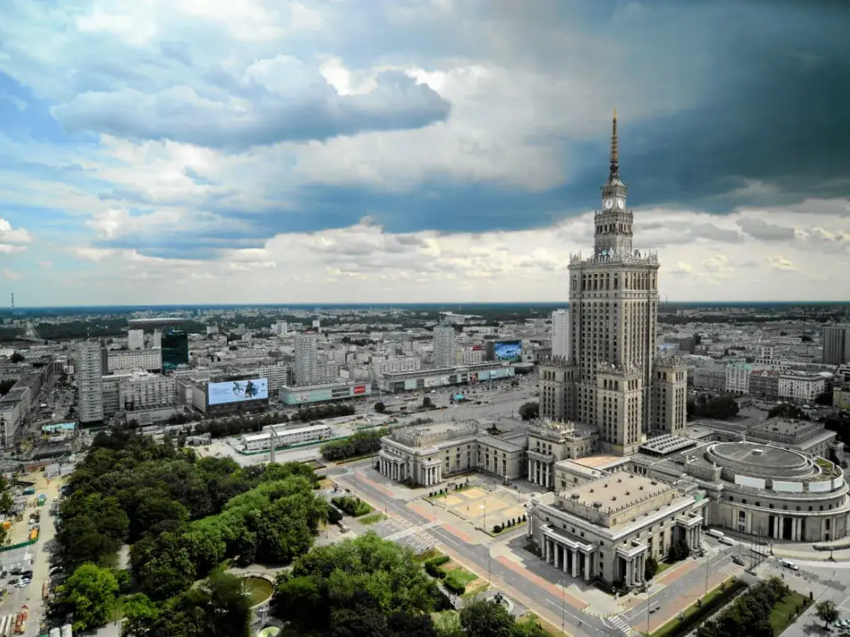 Warszawa opis: Pałac Kultury i Nauki góruje nad miastem, otoczony nowoczesnymi budynkami i zielenią.
