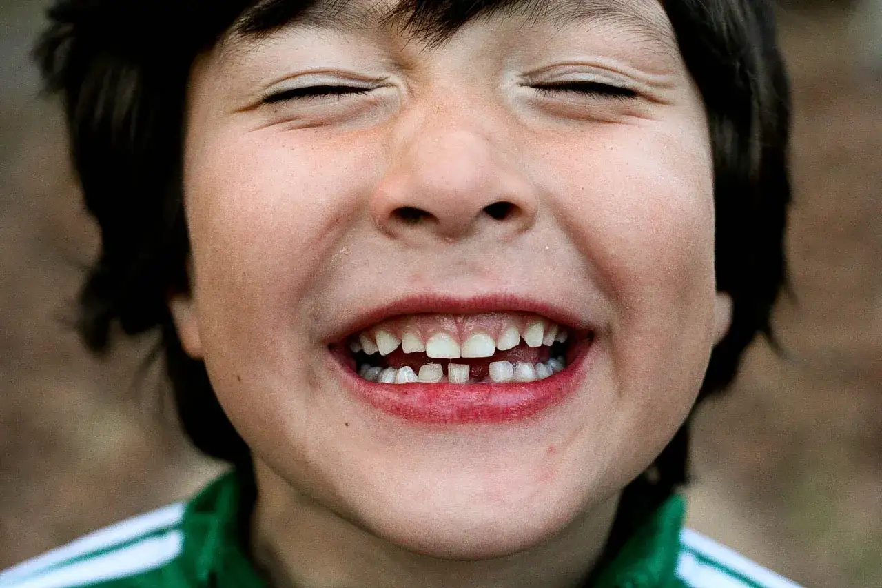 Niño sonríe con los ojos cerrados, mostrando un hueco donde se me ha caído un diente. ¡Qué emoción!