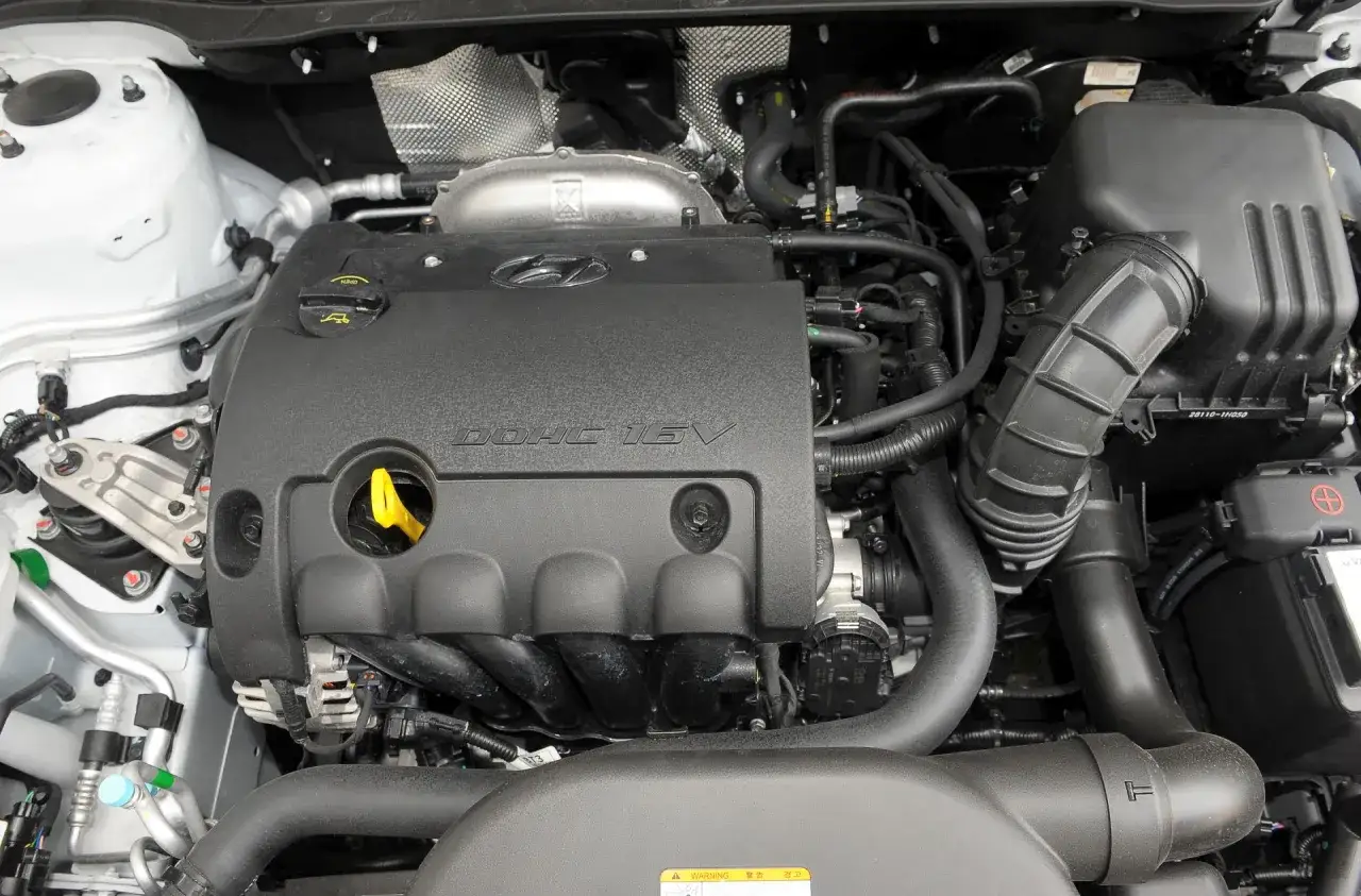 Silnik Hyundai i30 1.4 benzyna. Widoczny czarny kolektor, żółta miarka oleju i elementy układu dolotowego.