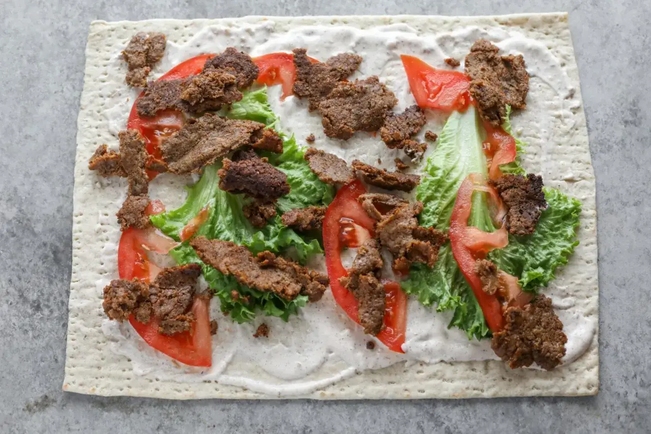 Kebab na tortilli z sałatą i pomidorami, sos. Pyszny, ale warto sprawdzić kebab kcal przed zjedzeniem.