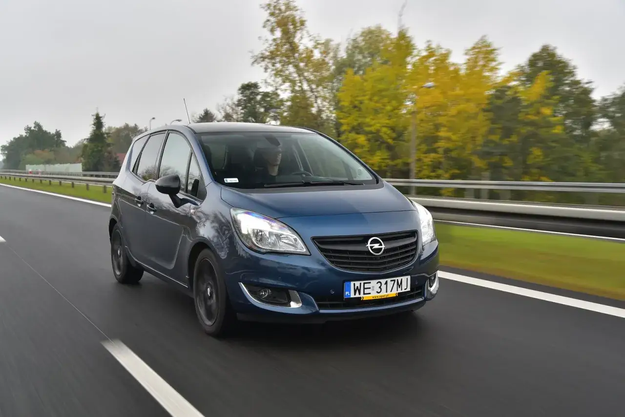 Niebieski Opel Meriva 1.4 benzyna jedzie autostradą wśród jesiennych drzew.