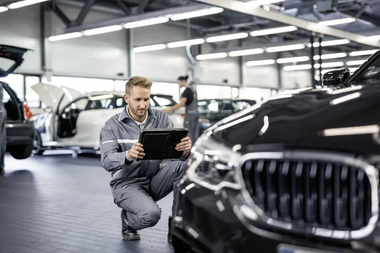 T&eacute;cnico revisa datos en tablet para mantenimiento BMW X1. Opiniones positivas sobre el servicio.