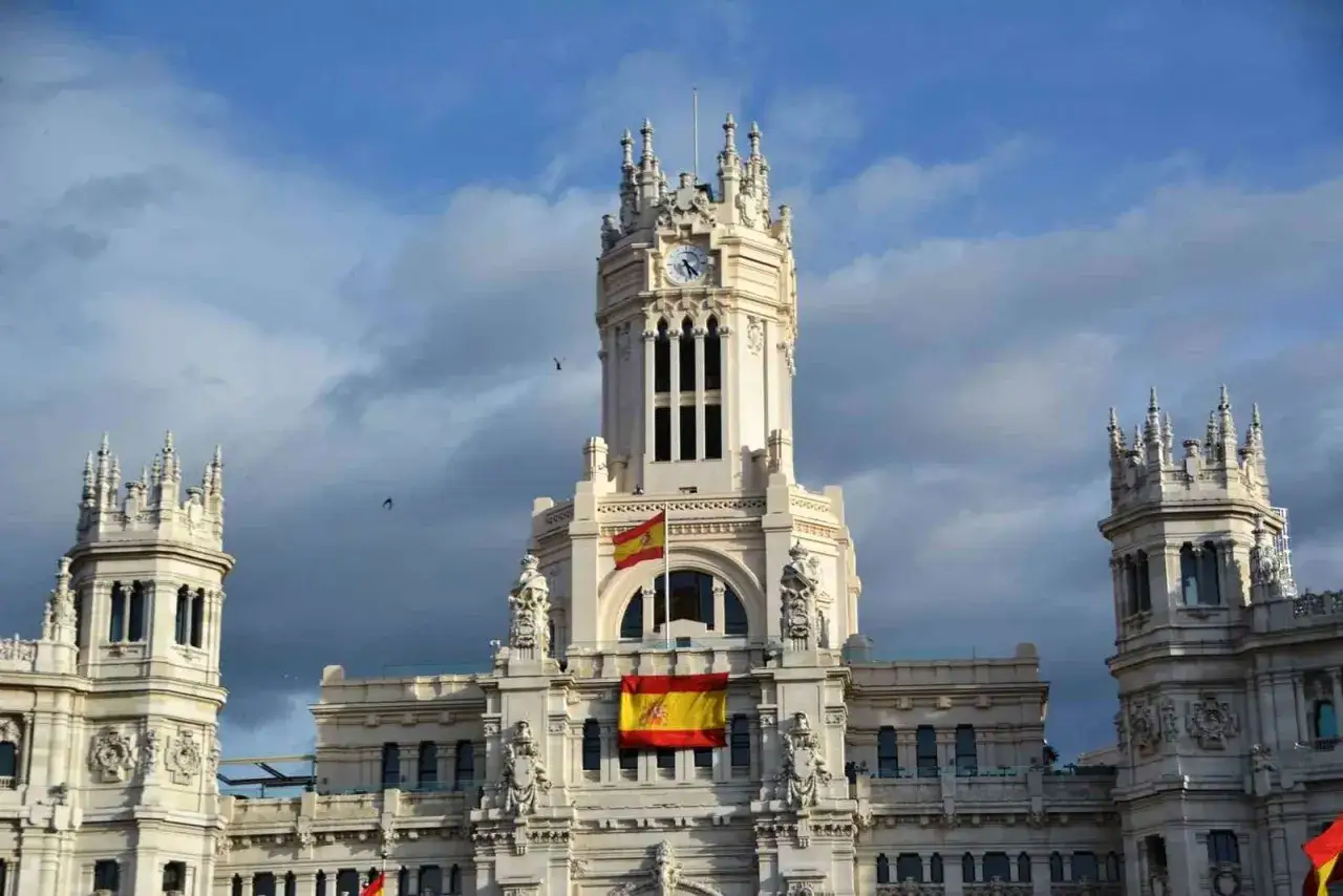 Palacio de Cibeles con banderas españolas, un lugar ideal para empezar a descubrir las 10 cosas que hacer en Madrid.
