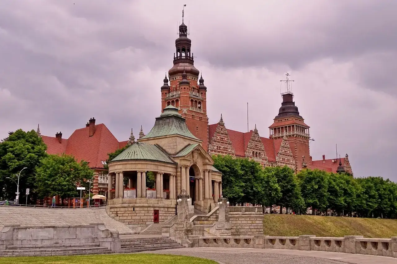 Majestatyczne budowle na szczecińskim Starym Mieście, z charakterystycznymi wieżami i czerwonymi dachami, otoczone zielenią.