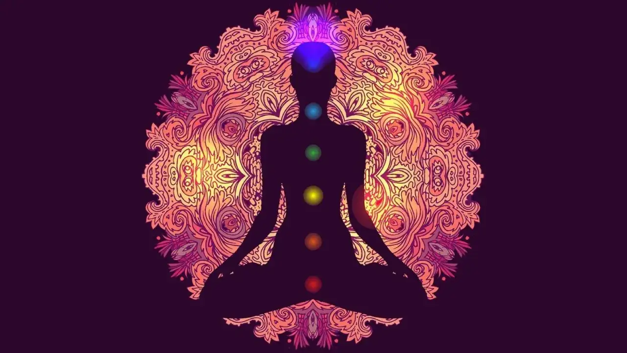 Sylwetka w pozycji medytacyjnej z kolorowymi czakrami, symbolizująca przebudzenie kundalini na tle mandali.