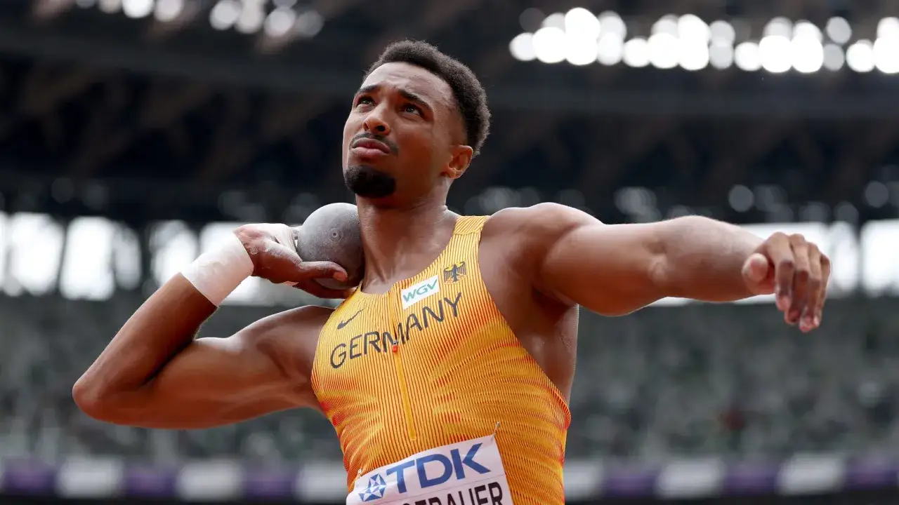 Ein Athlet in deutscher Sportkleidung bereitet sich auf den Kugelstoß vor, eine der zehnkampf disziplinen.