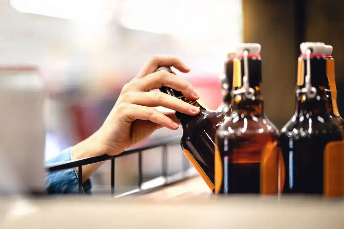 Ręka wybiera butelkę piwa. Alkohol etylowy w jedzeniu, jak piwo, jest popularnym wyborem.
