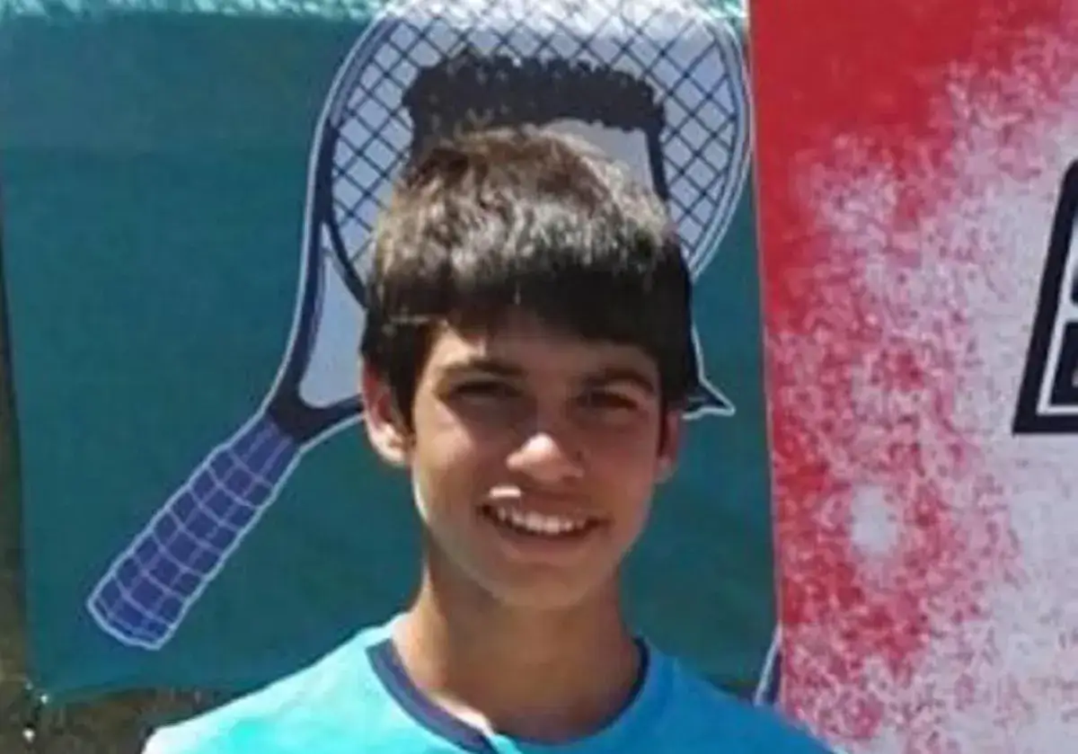 Joven Carlos Alcaraz sonríe, listo para la final. Detrás, un fondo con raqueta de tenis.