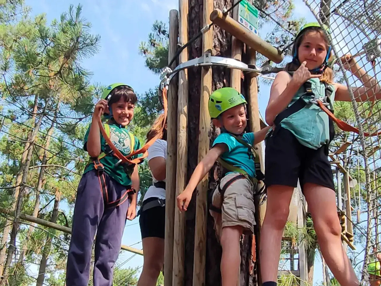 Enfants souriants et casqués, prêts pour l'aventure dans un camp sportif accrobranche.