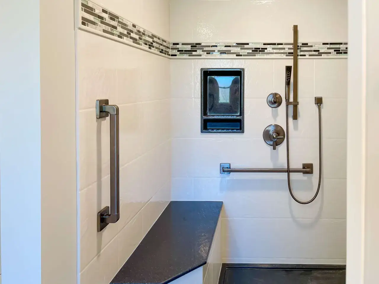 A modern shower with white tiles, a dark granite bench, and a sleek grab bar installation for safety and style.