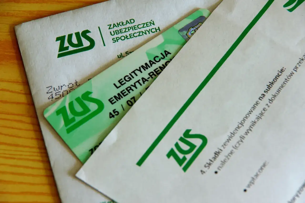 Nowa legitymacja emeryta rencisty ZUS na drewnianym tle. Dokumenty z zielonym logo ZUS.