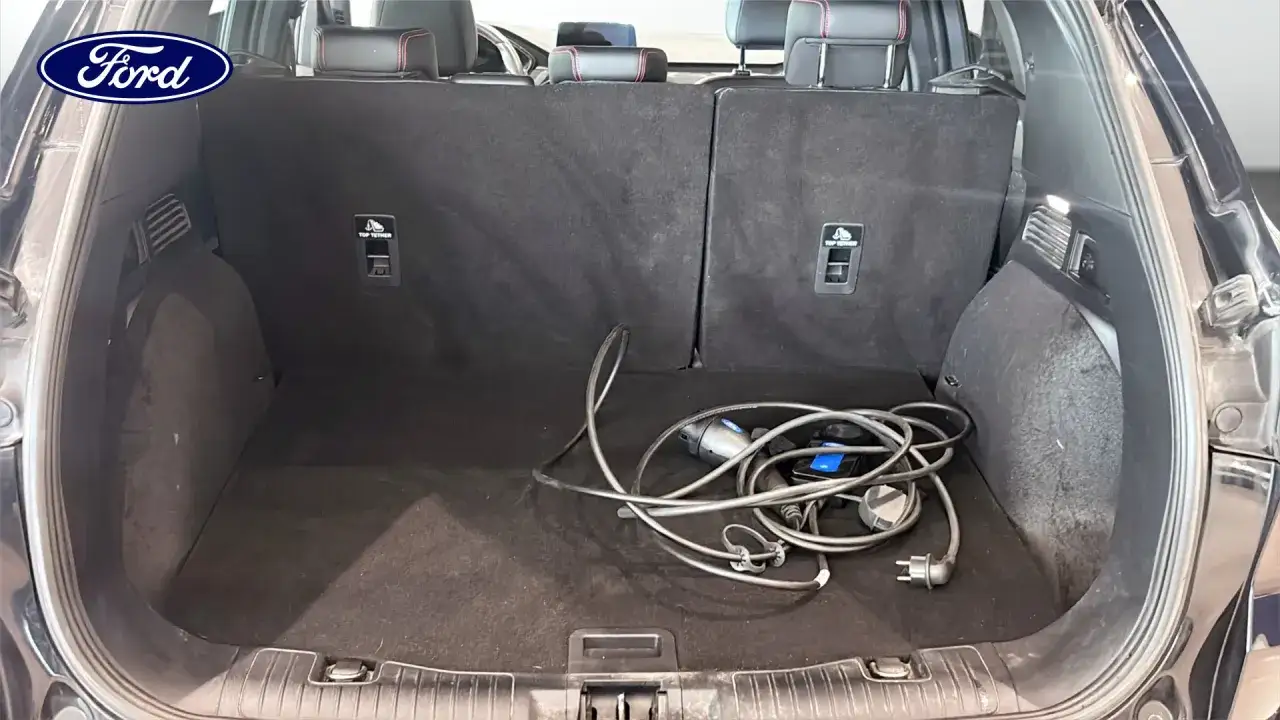 Bagageutrymmet i en begagnad Ford Kuga, redo för ett test. Laddningskabeln ligger prydligt hoprullad.