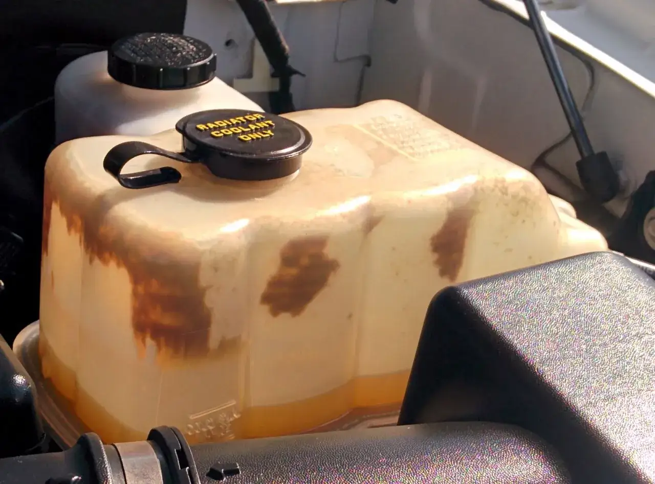 The coolant reservoir shows brown discoloration, raising the question: does antifreeze expire? This suggests the coolant may be old and less effective.