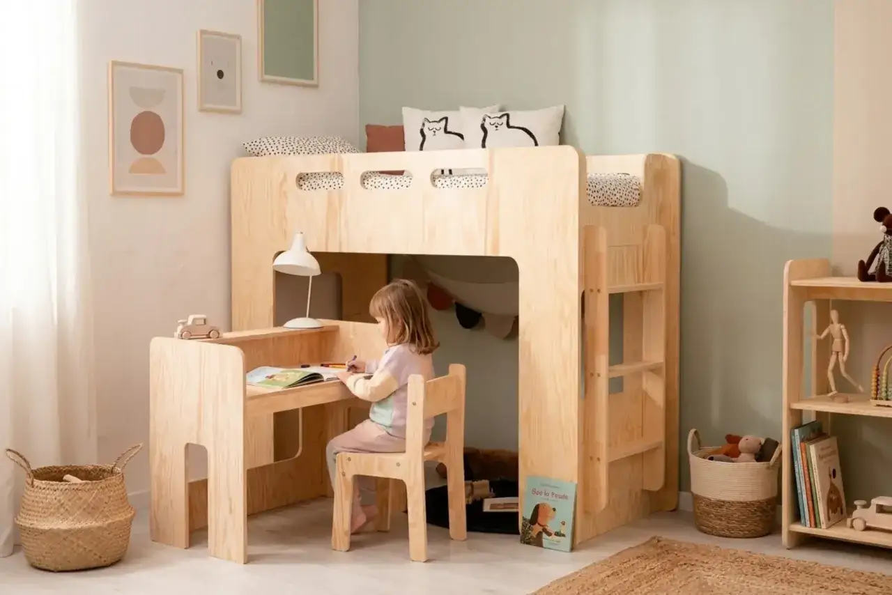 Une petite fille dessine à son bureau sous un lit mezzanine en bois. Une belle idée déco chambre enfant, chaleureuse et fonctionnelle.