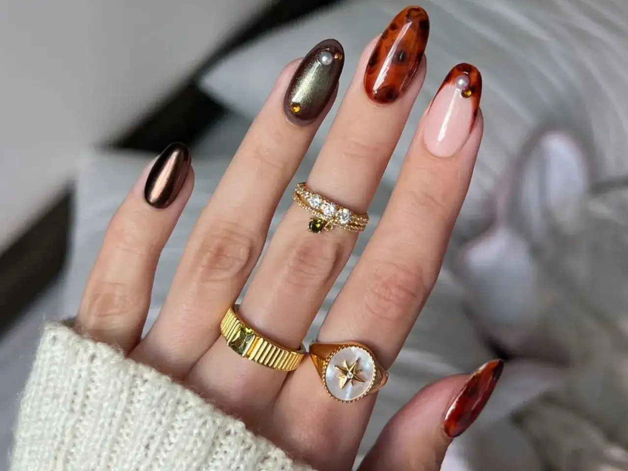 Main d'une femme portant des bijoux et des ongles orn&eacute;s d'un motif &eacute;caille de tortue.