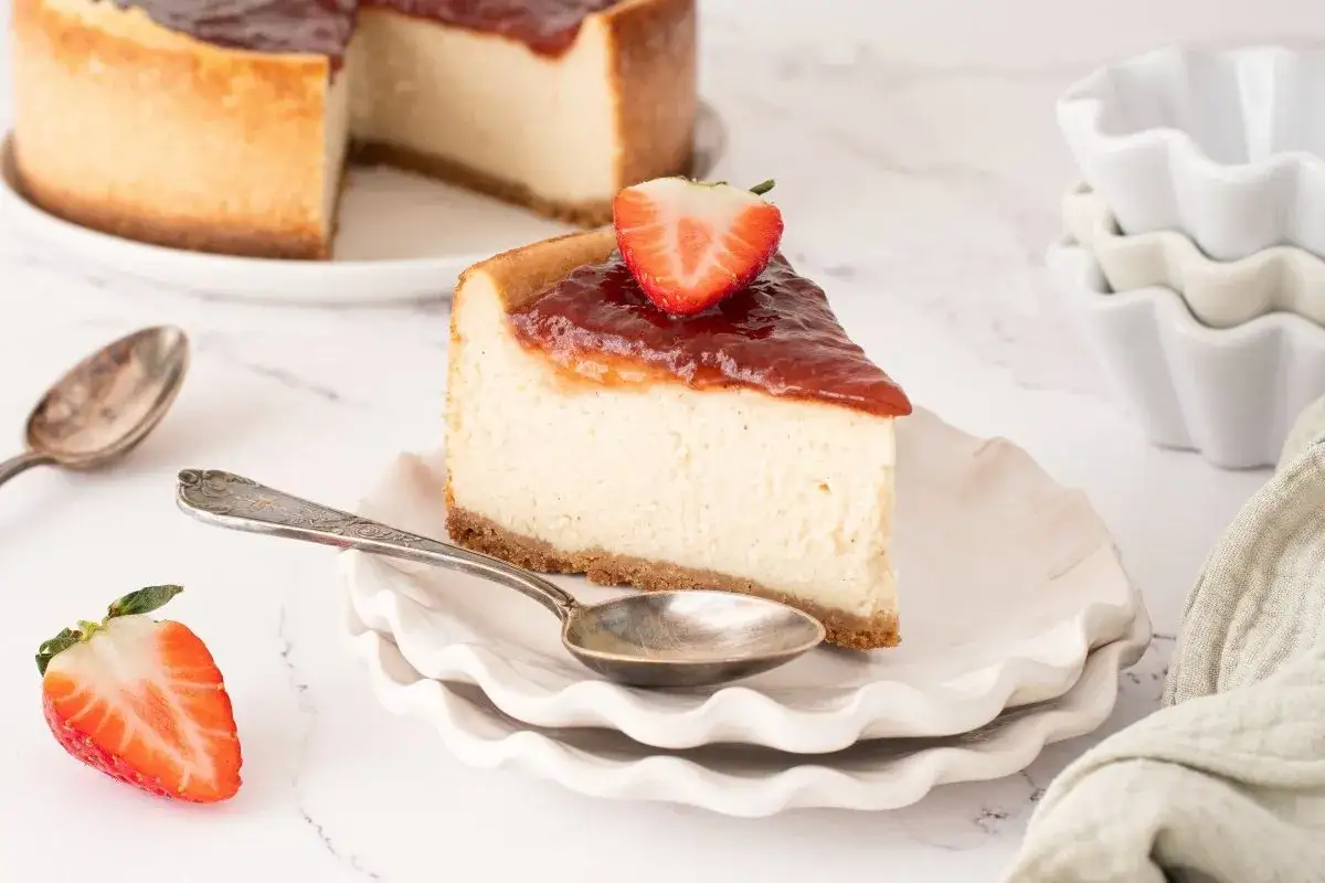 Deliciosa tarta de queso vegana con cobertura de fresa y una fresa fresca encima.