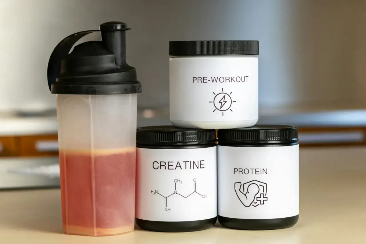 Shaker z napojem i puszki z odżywkami: kreatyna, pre-workout, protein. Wyb&oacute;r między kreatyną jabłczan czy monohydrat?