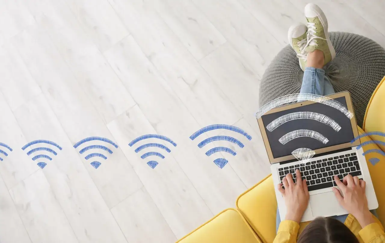 Persona naviga in internet a casa senza fibra, con segnali Wi-Fi disegnati che si estendono dal laptop.