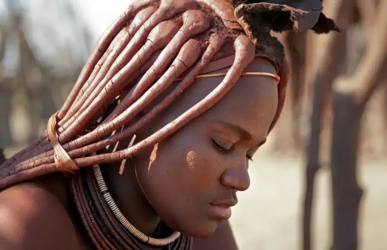Portret kobiety z plemienia Himba w Namibii. Jej włosy ułożone są w charakterystyczne, gliniane dredy.