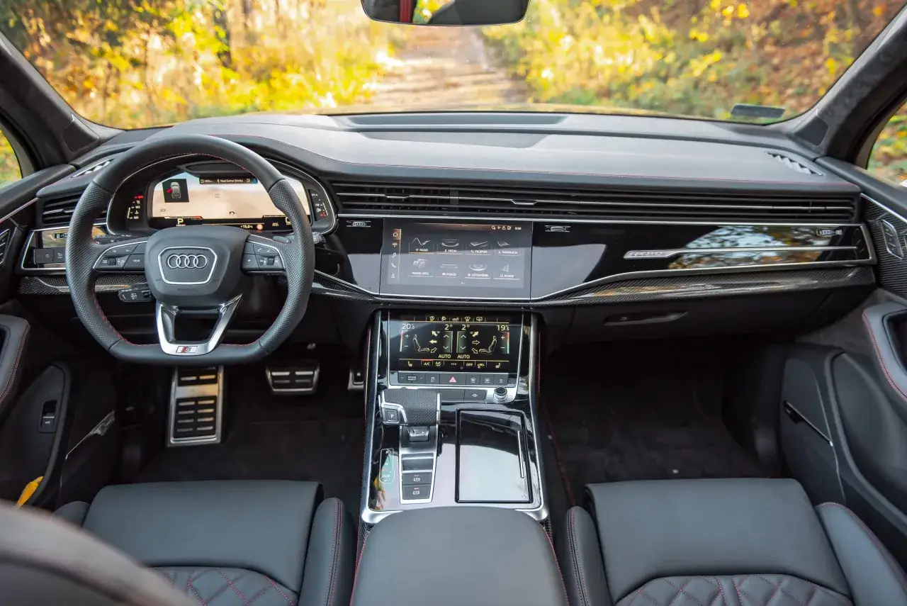 Wnętrze Audi Q7 z cyfrowymi ekranami, kierownicą i eleganckimi detalami.