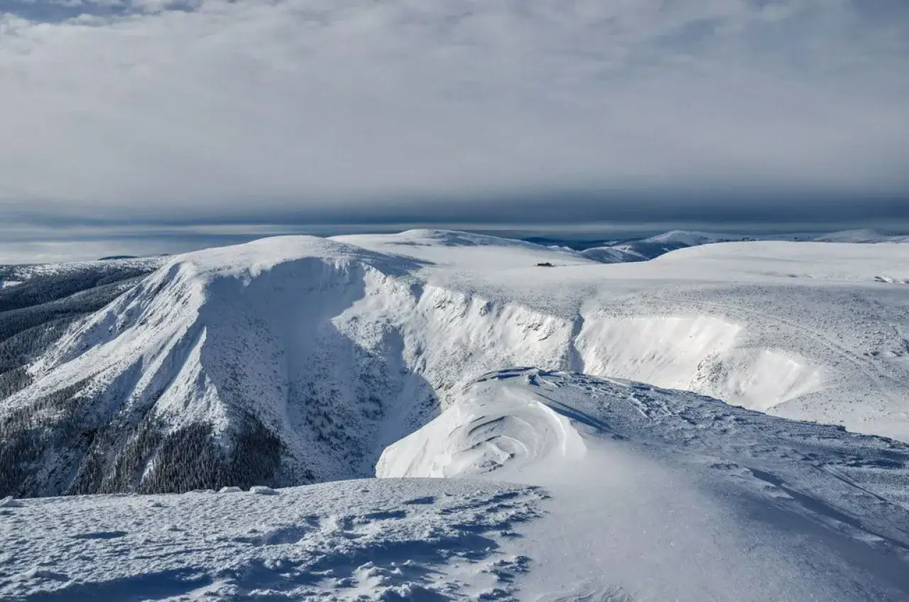 Schneebedeckte Berge im Riesengebirge Skigebiet. Eine weite, winterliche Landschaft mit sanften Hängen und tiefen Tälern, ideal für Wintersport.