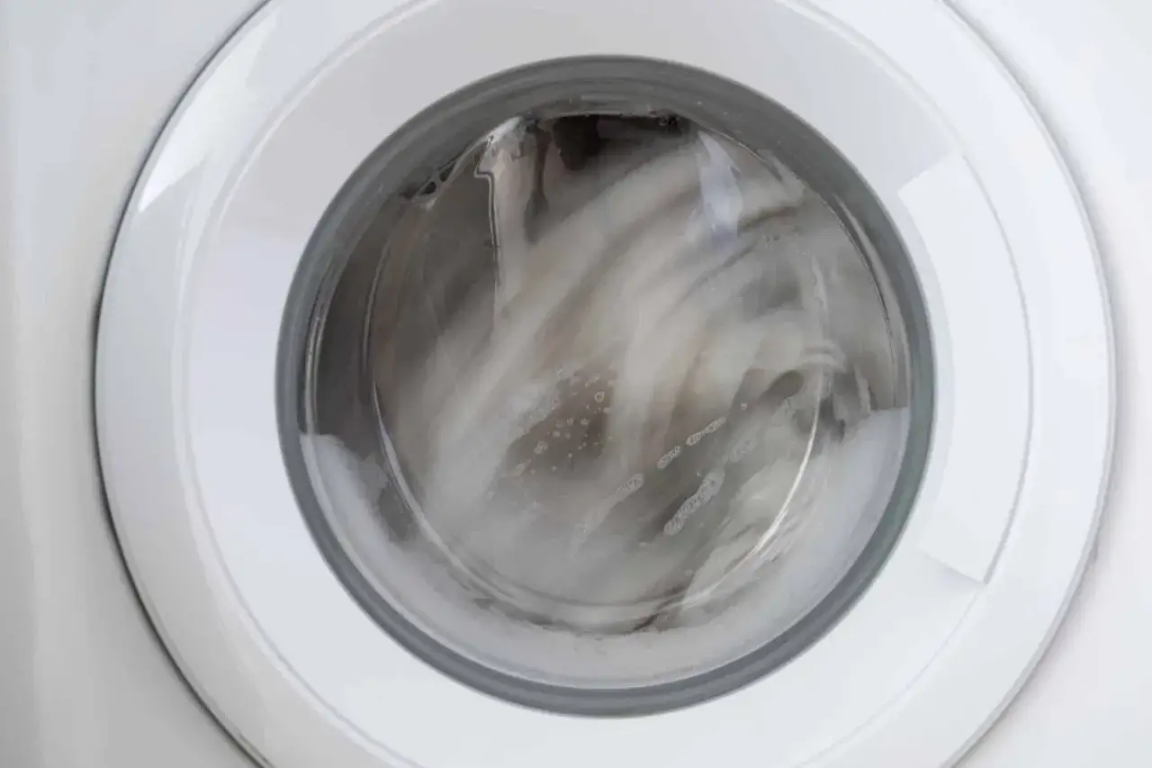 Interior de una lavadora en pleno centrifugado, con la ropa y la espuma movi&eacute;ndose r&aacute;pidamente.