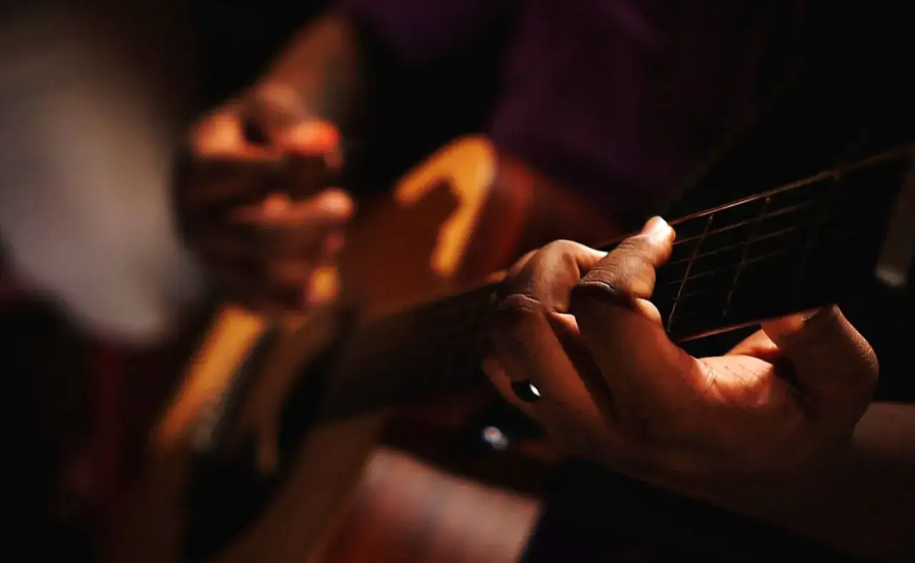 Manos tocando guitarra, creando un soniquete que es pura emoción.
