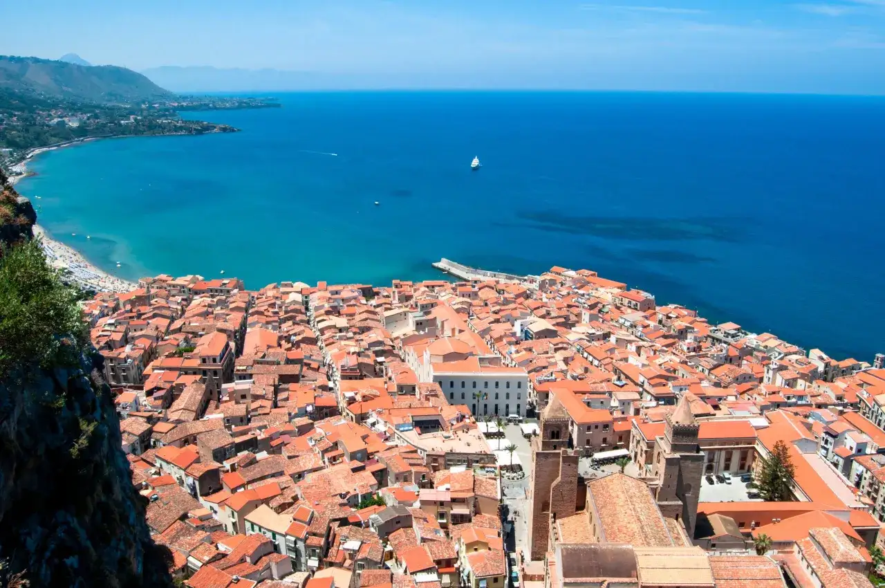 Widok na Cefalu, Sycylia, z dachu z widokiem na morze i miasto z czerwonymi dachami.